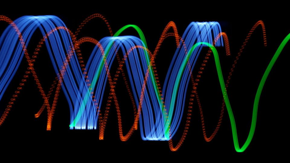 Abstract colorful light trails forming wave patterns against a dark background.
