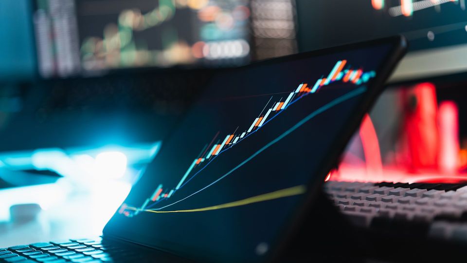Tablet displaying a rising stock market chart with candlestick data.