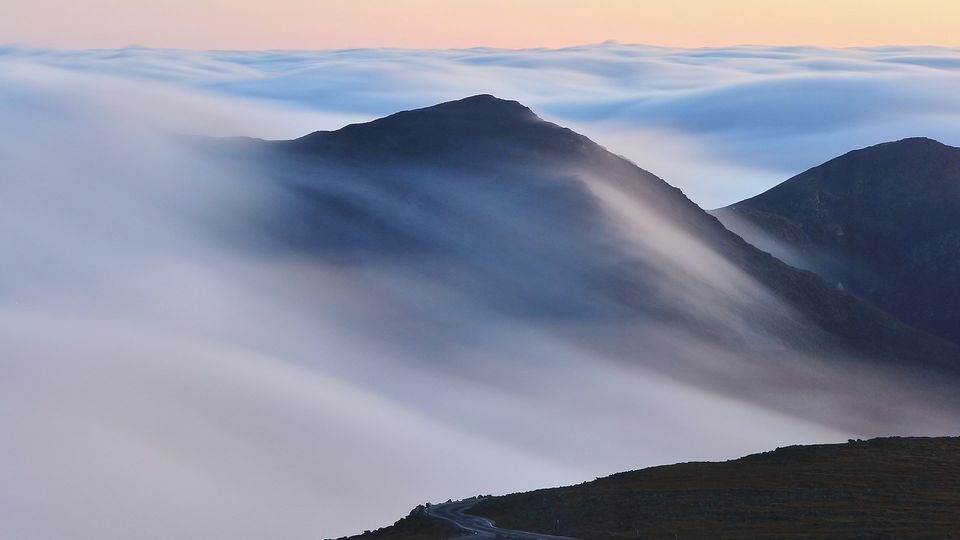Mountain peaks rising above a sea of clouds at sunrise.