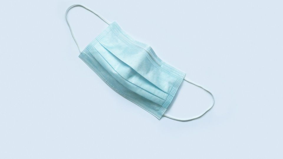 Disposable surgical face mask on a white background.
