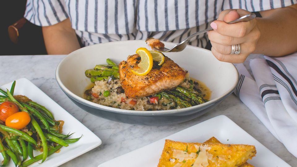 Grilled salmon fillet with asparagus and rice, served in a restaurant meal with fresh vegetables.