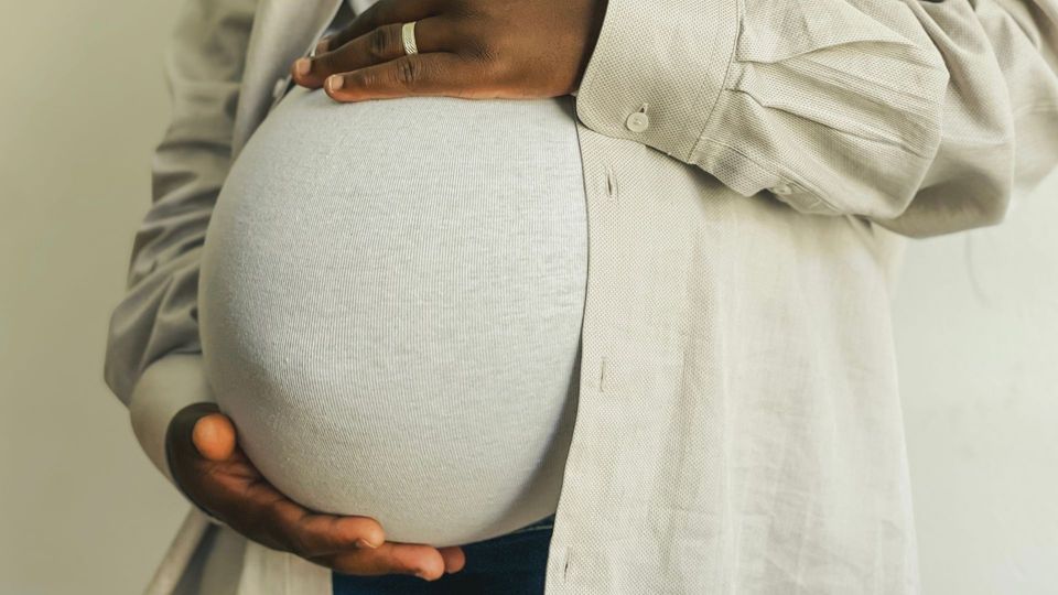 Pregnant woman gently holding her baby bump.