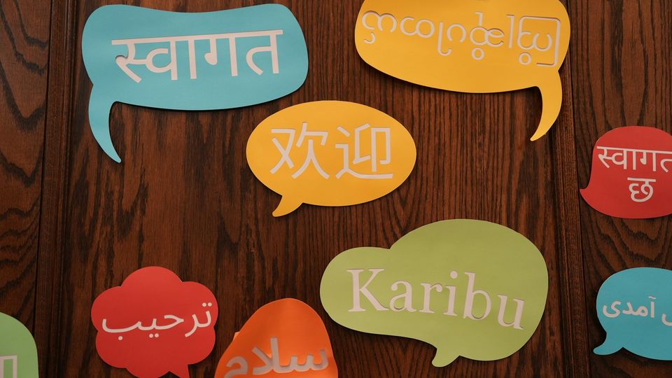Colorful speech bubbles displaying welcome messages in multiple languages.