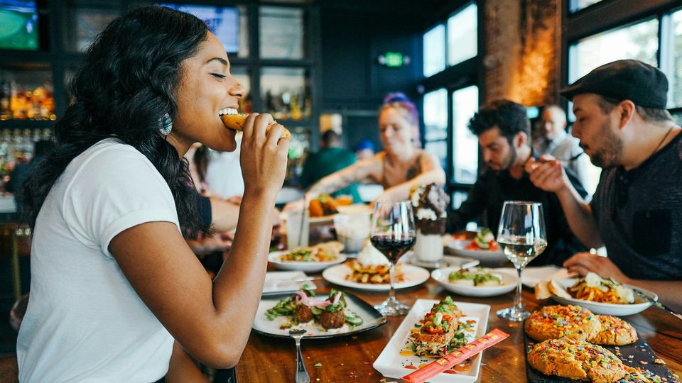 Woman enjoying a meal with friends at a restaurant table.