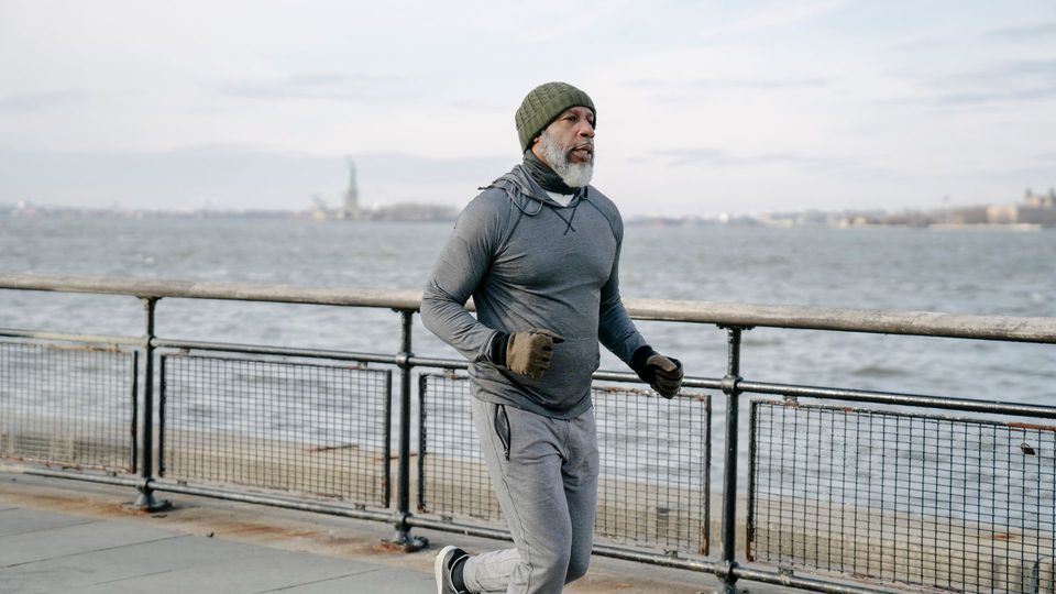 Person jogging along a waterfront promenade in cold weather.