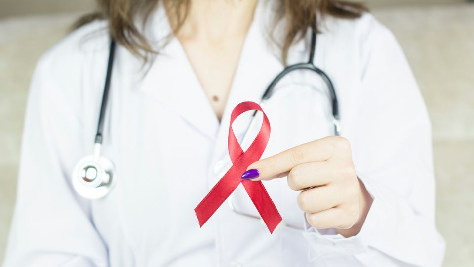 A doctor holding up a red awareness ribbon, representing HIV and AIDS awareness