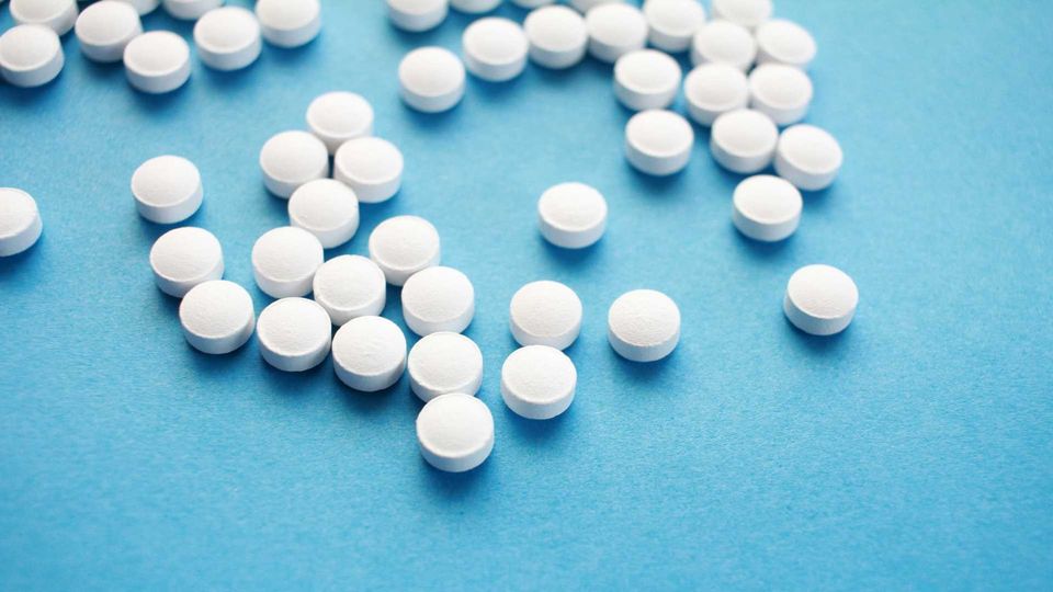 A collection of small round medication pills scattered across a blue surface.