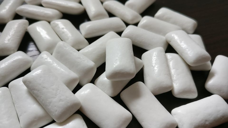 White squares of chewing gum, scattered over a black surface.