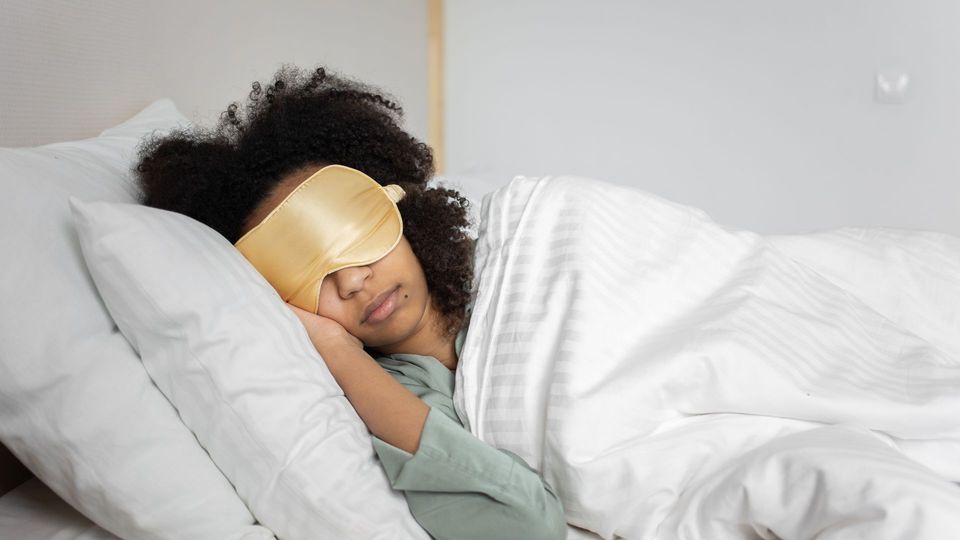 Woman sleeping in bed with a silk sleep mask.