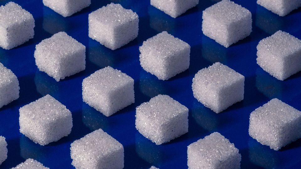 Sugar cubes arranged in a geometric pattern on a blue surface.