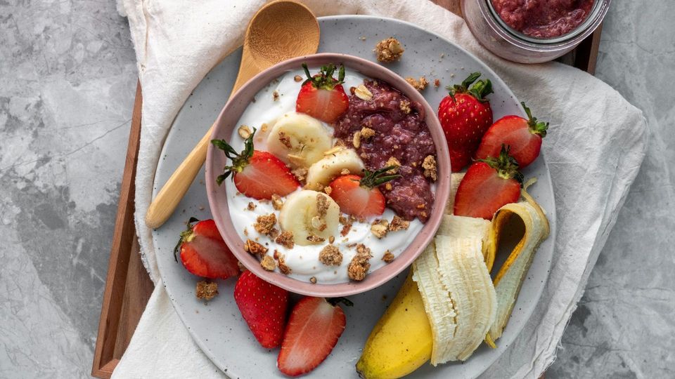 Yogurt bowl topped with strawberries, banana slices, and granola.