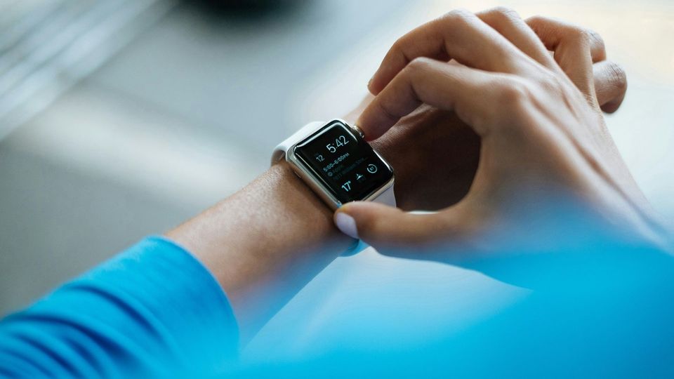 Person adjusting a smartwatch on their wrist, which displays health and activity data.