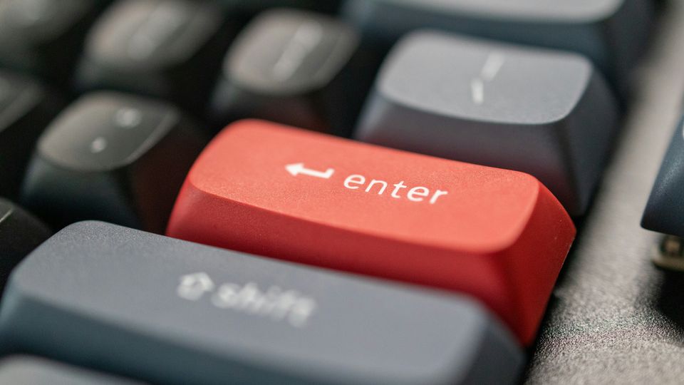 A close-up photograph of a black keyboard with a red "Enter" key.