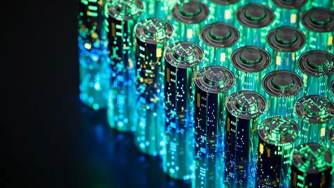 Collection of batteries standing in rows. The batteries have a futuristic hologram overlay of glowing green, yellow, and blue lines and dots. 