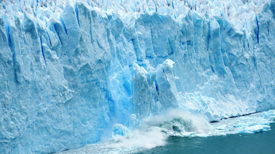 Blue glacier cliff towering above icy water.