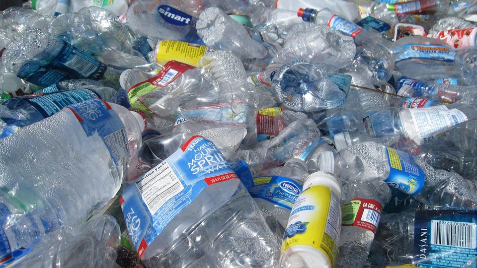 A pile of waste plastic bottles, clean but crumpled, ready for recycling.