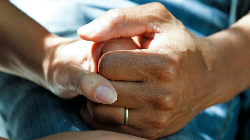 Couple clasping hands in a comforting gesture.