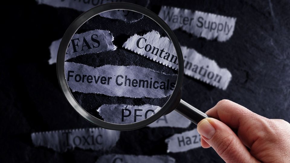 Magnifying glass highlighting PFAS "forever chemicals" and water contamination headlines.
