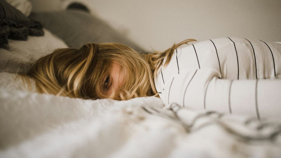 Woman lying on a bed with her head resting on a pillow.