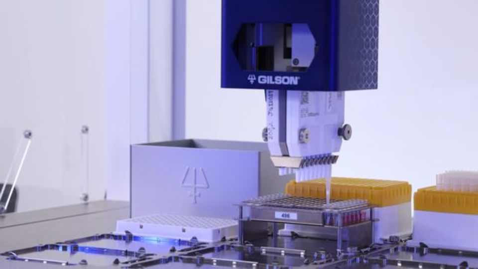 Automated Gilson liquid handling system pipetting samples into a 96-well plate in a laboratory.