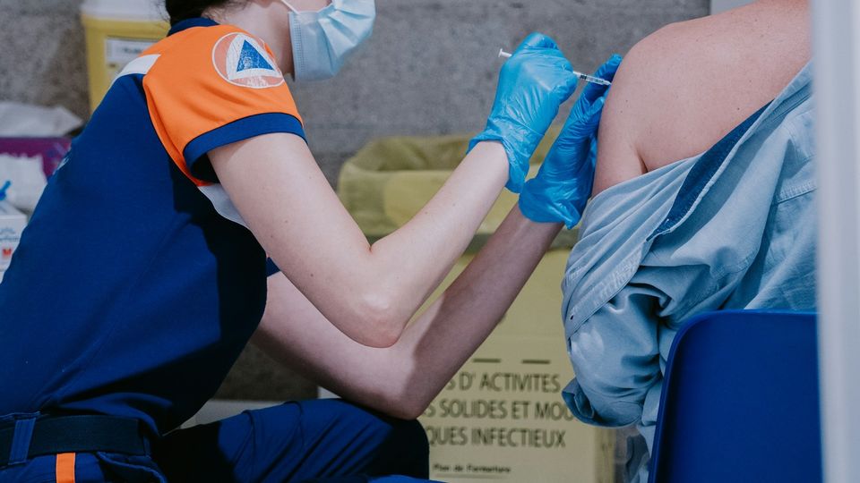 Healthcare worker administering a vaccination in a patient's upper arm.