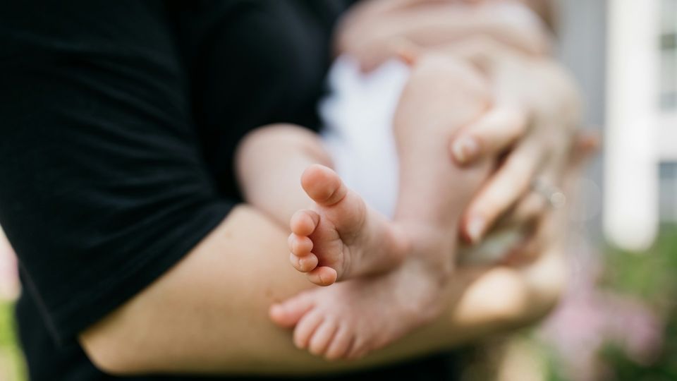 Parent holding a baby outdoors.