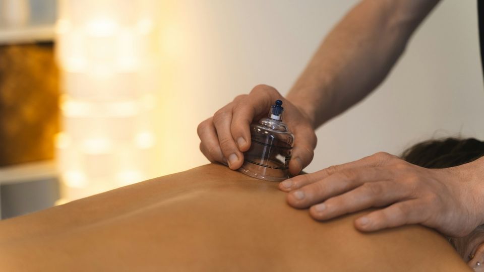 Therapist performing cupping therapy on a person's back with a suction cup.