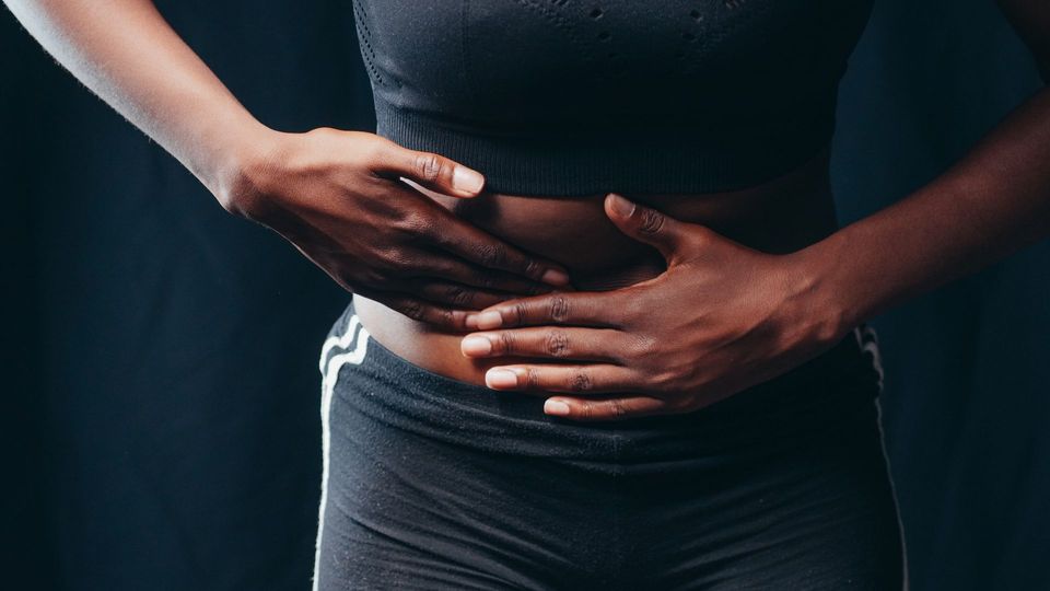 Close-up of a person pressing hands on abdomen, indicating discomfort or pain.