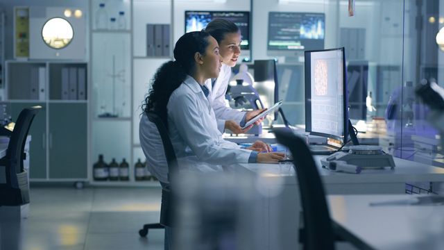 Two female researchers reviewing data on a computer in a laboratory. 
