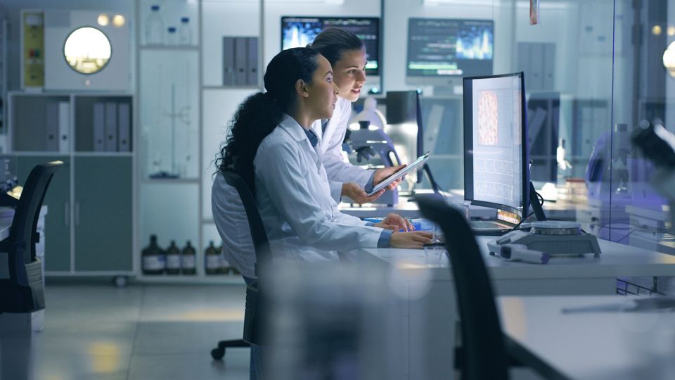 Two female researchers reviewing data on a computer in a laboratory.