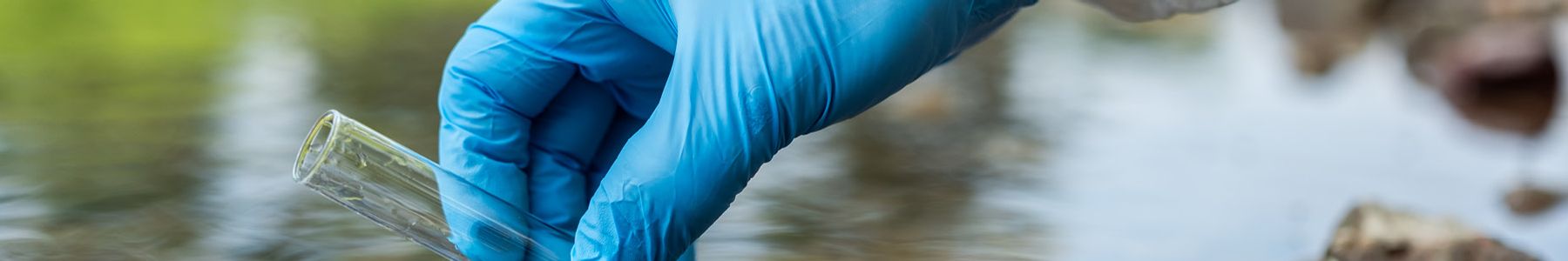 Laboratory technician collecting a water sample for automated microplastic analysis to support water quality research. 