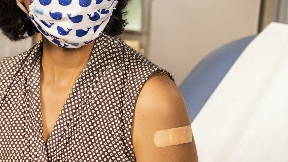 Close-up of a woman in bandage on her upper arm after receiving an injection or vaccine.