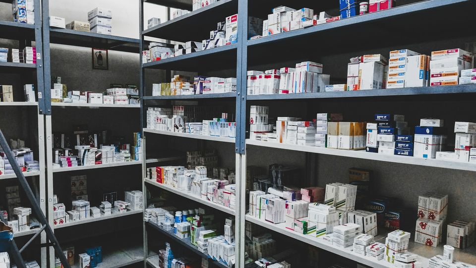 Pharmacy shelves stocked with prescription medicines and pharmaceutical products.