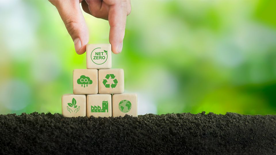 Sustainable GC and GC/MS performance illustrated with hand stacking net zero and recycling blocks on soil.