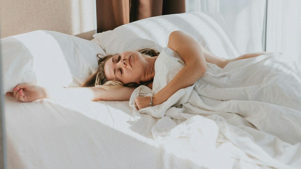 Woman sleeping peacefully in bed under white bedding.
