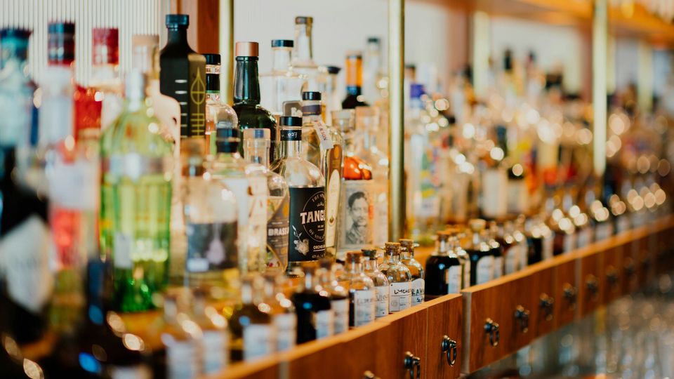 Bottles of alcoholic spirits on a bar shelf.