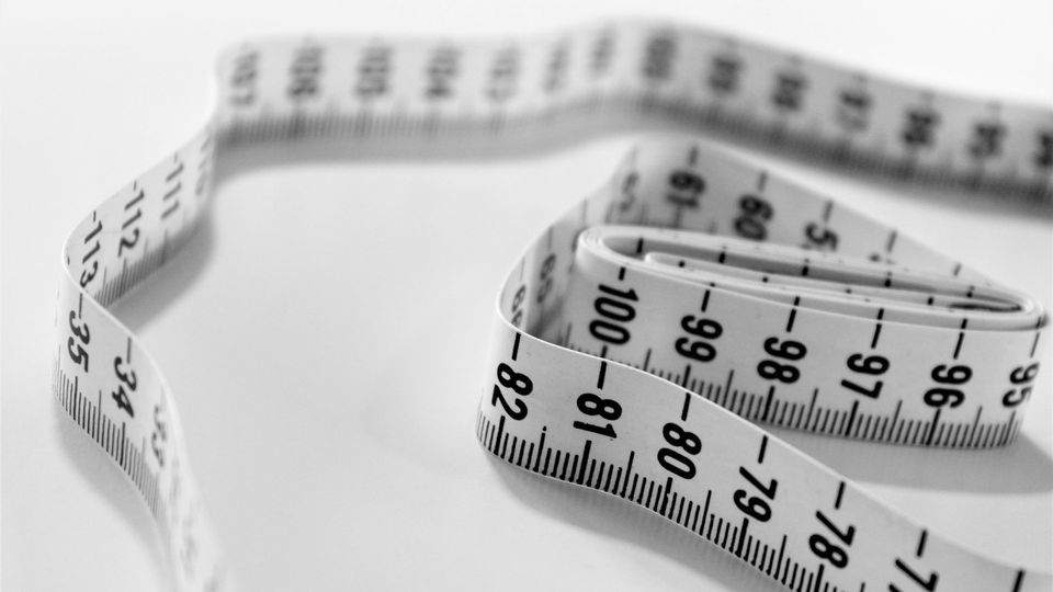 Flexible measuring tape coiled on a white surface.