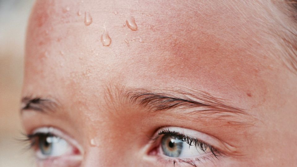 Close-up of sweat droplets on a person's forehead.