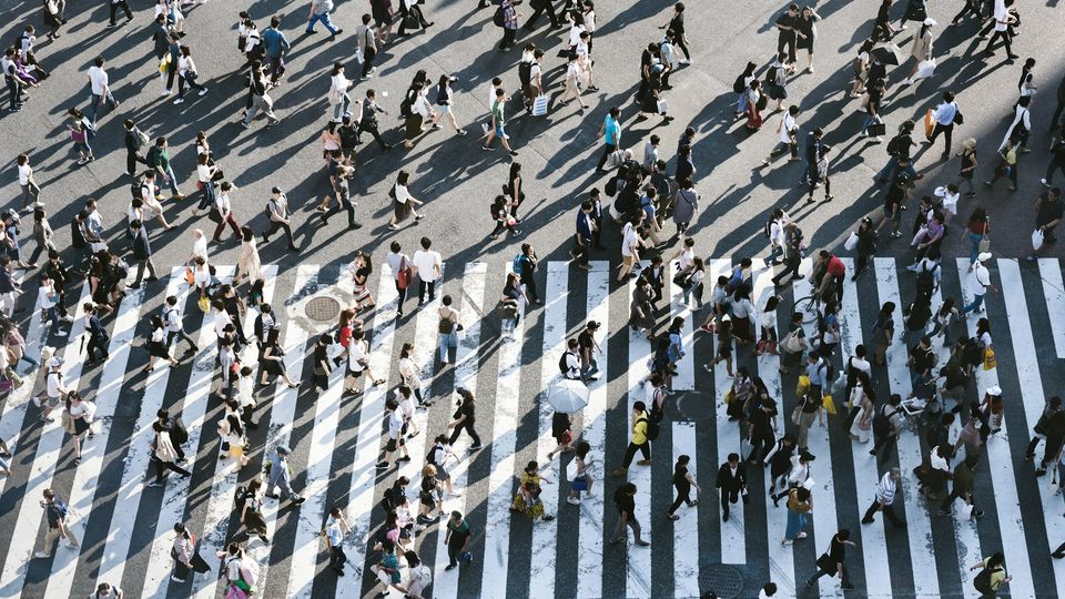 An arial photo of people crossing a zebra crossing in a city.