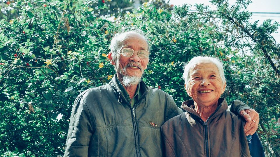 An old couple, smiling at the camera.