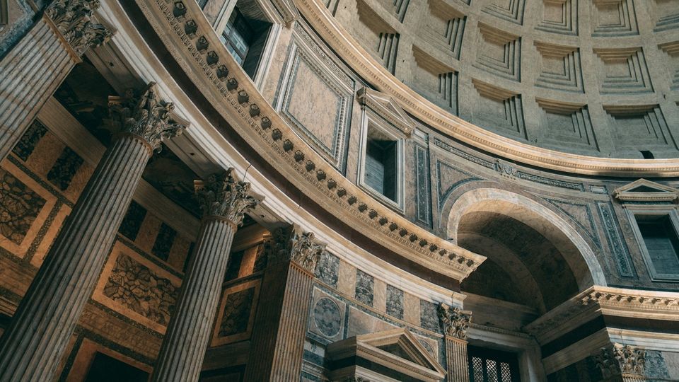 Interior of the Pantheon with towering marble columns and a coffered dome.