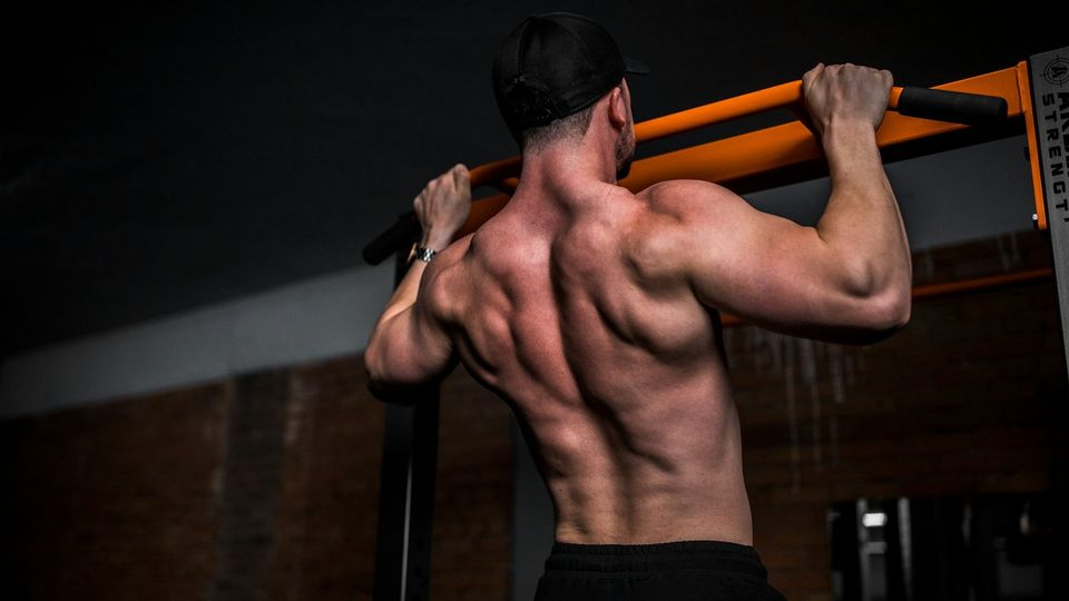 Man performing pull-ups on a gym bar to build upper body and back strength.