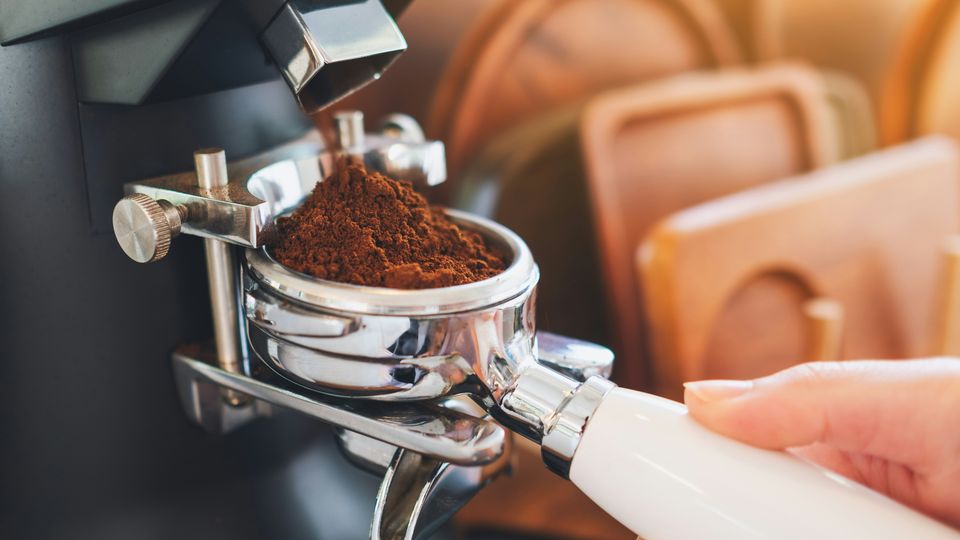 A barista loading coffee grounds into a portafilter.