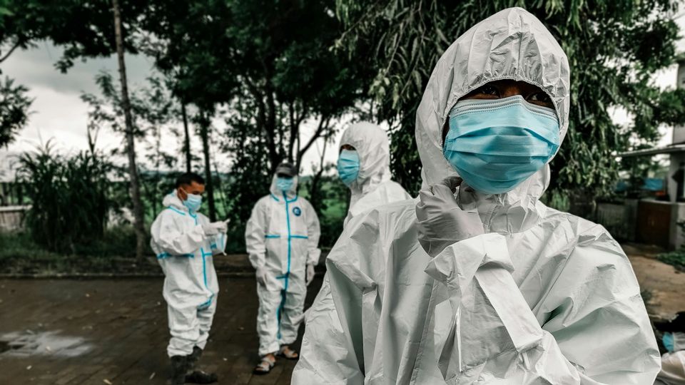 Health workers wearing protective suits and face masks during a public health response.