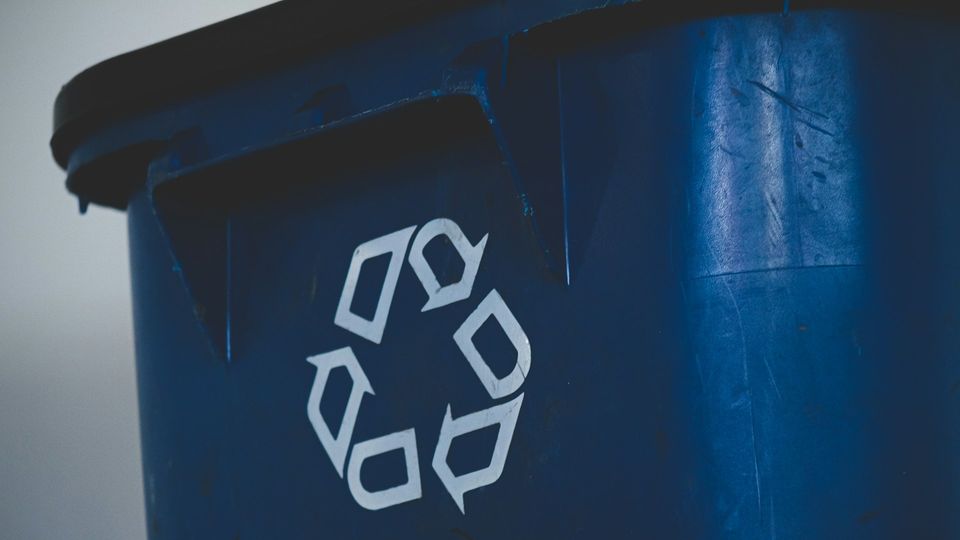 Blue recycling container with a white recycling symbol.