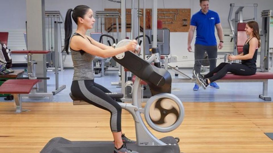 Women using exercise machines in a modern gym.