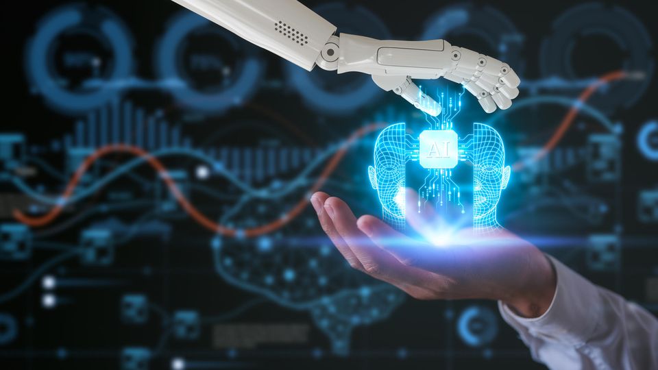 A hologram of an AI chip within a human mind, held between a human hand and a robotic hand.