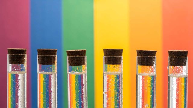 Test tubes lined up against a rainbow backdrop. 