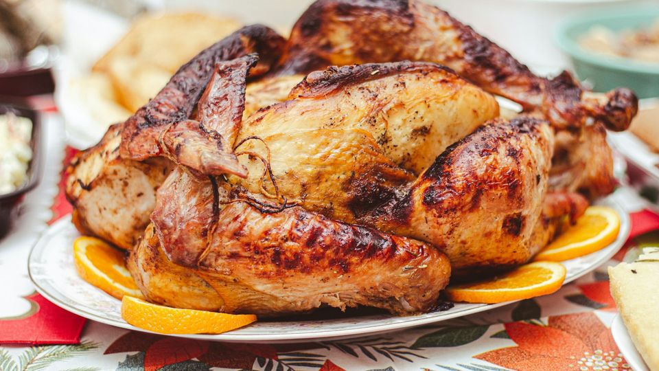 Roasted whole chicken on a serving platter with orange slices.