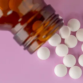 White tablets spilling from an amber bottle, illustrating nitrosamine analysis.